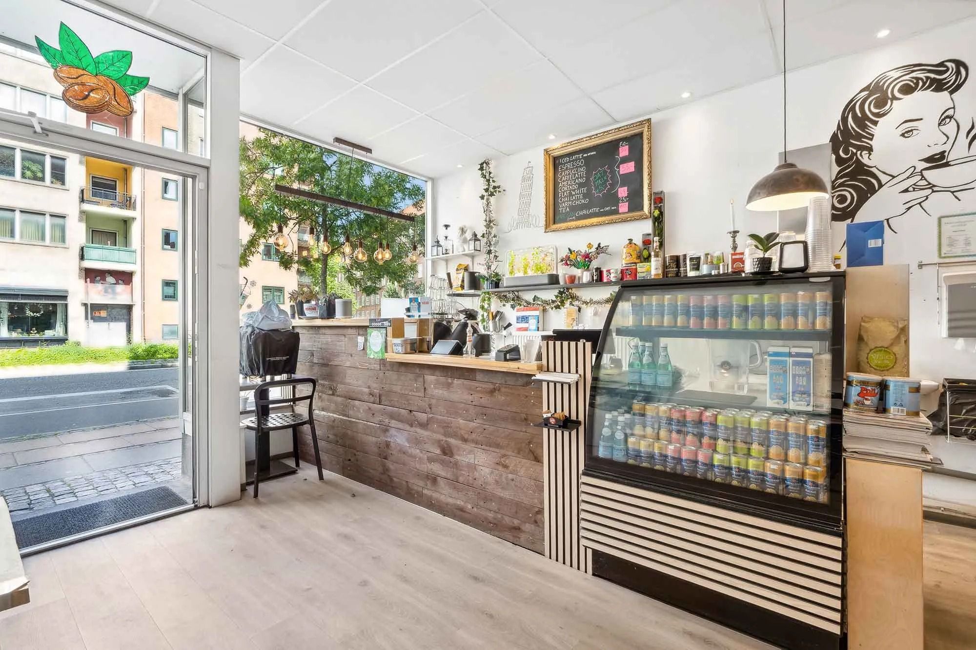 Moderne café med trædisk og glasvæg, krydrede drikkevarer og smagfulde kager og slik