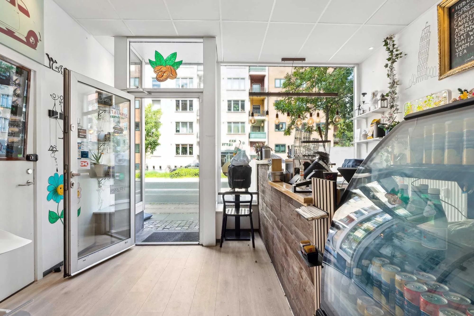 Foto af en café med en stor glasvindue og træhylder med varer og drikkevarer