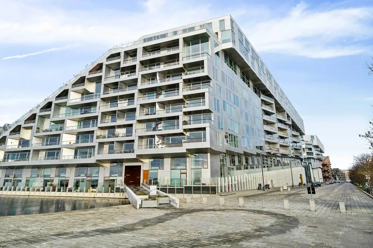 Moderne højhus med glasvinduer og terrasser ligger ved en havn. Strømlinet design med kæmpe glasflader og terrasser på hver