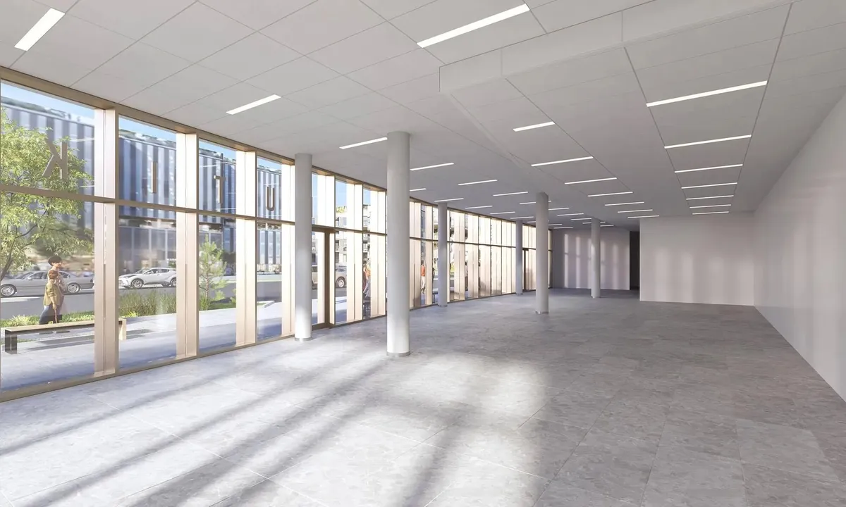 Et tomt, vellyst og moderne kontor med højloft og gul gulv og store vinduer med udsigt til gaden