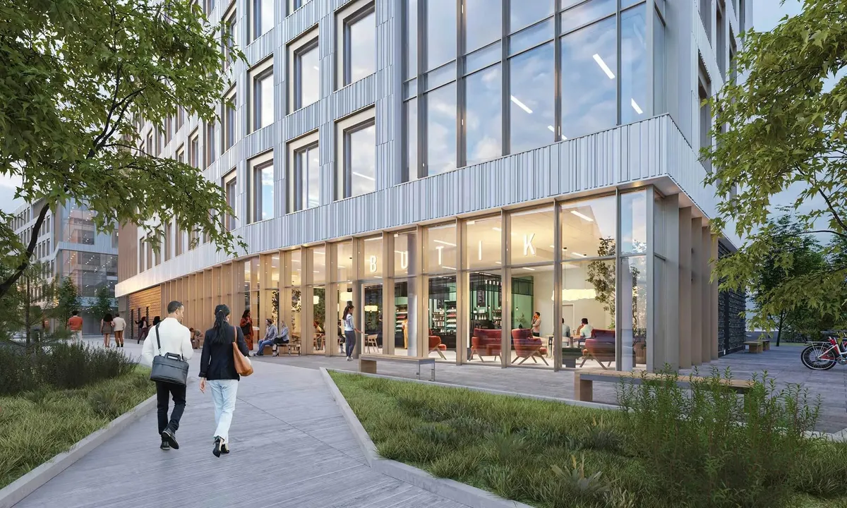 To personer går langs en gågade med store vinduer, hvor folk sidder og læser på træbænke