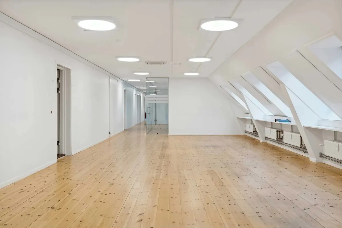 Ledig lokale til leje med lyse lofter og trægulv. Moderne kontorlokaler med højloftede rum og integrerede kølesystemer.