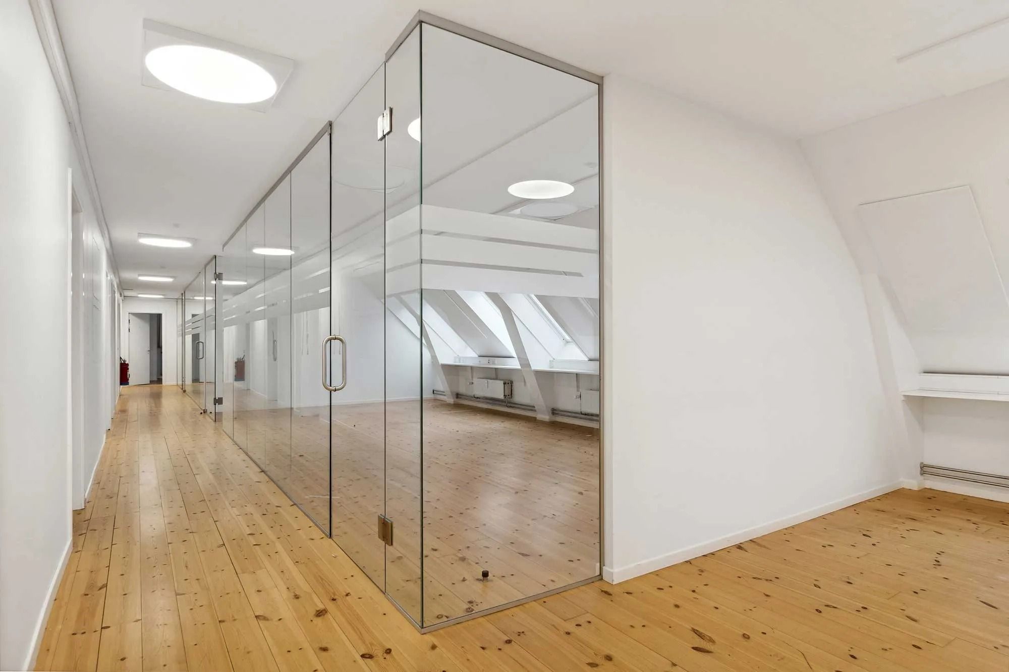 Moderne køkken med lyse lofter og glasdøre og højtloftede værelser med trægulve og hvide vægge