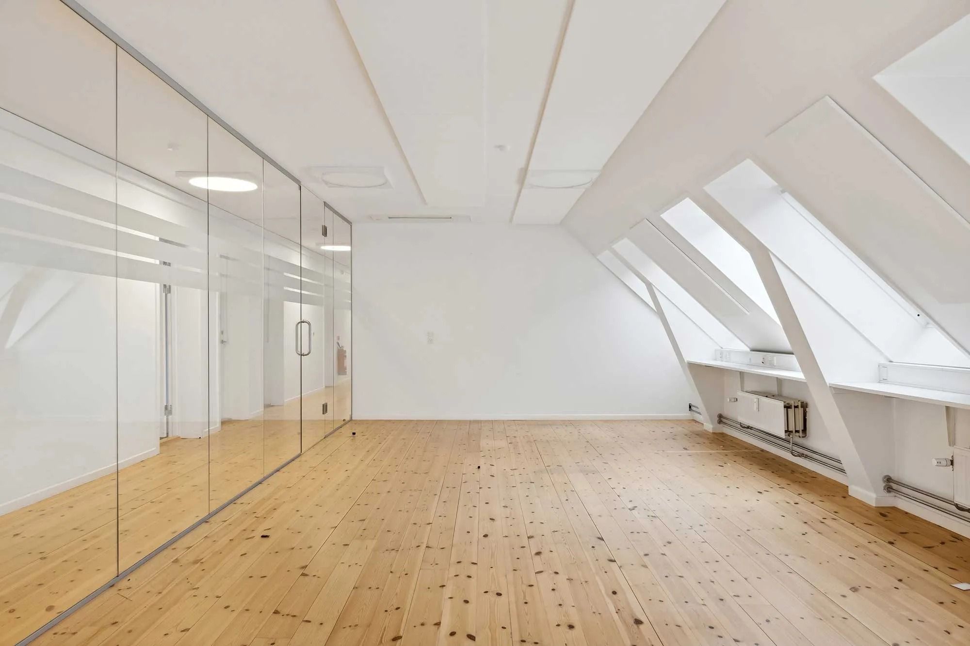 Lejemål med moderne design og loftsrum i træ og glas i et historisk bygningskompleks.