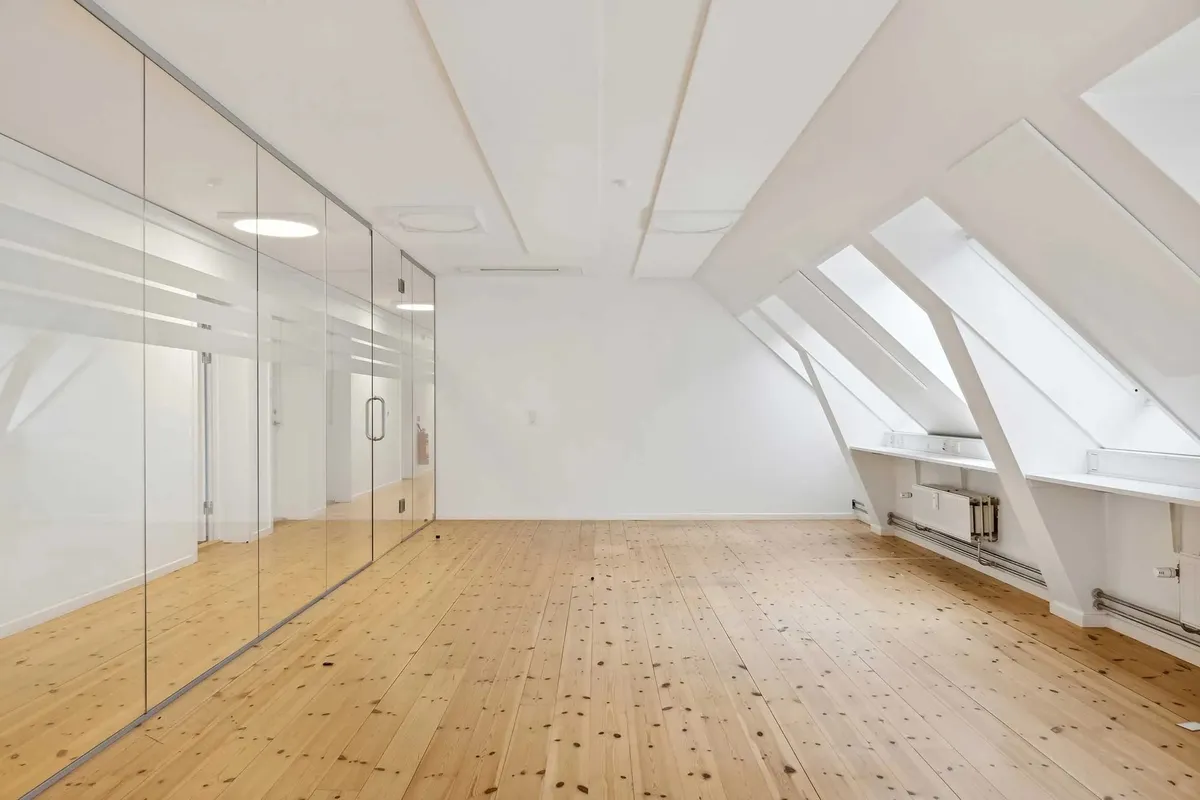 Lejemål med moderne design og loftsrum i træ og glas i et historisk bygningskompleks.