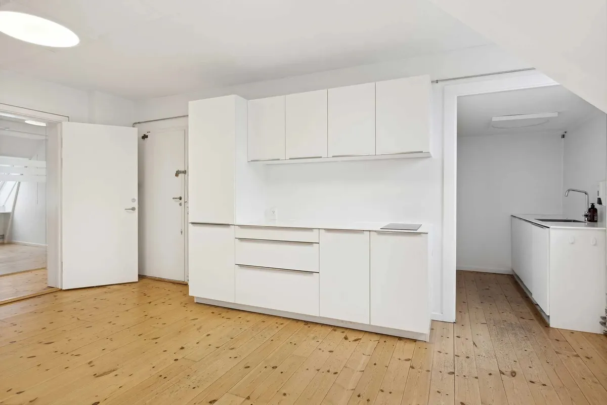 Lejlighed med køkken, hvidt skab og møbler, massivt trægulv og moderne interiørdesign med åbne døre og rum