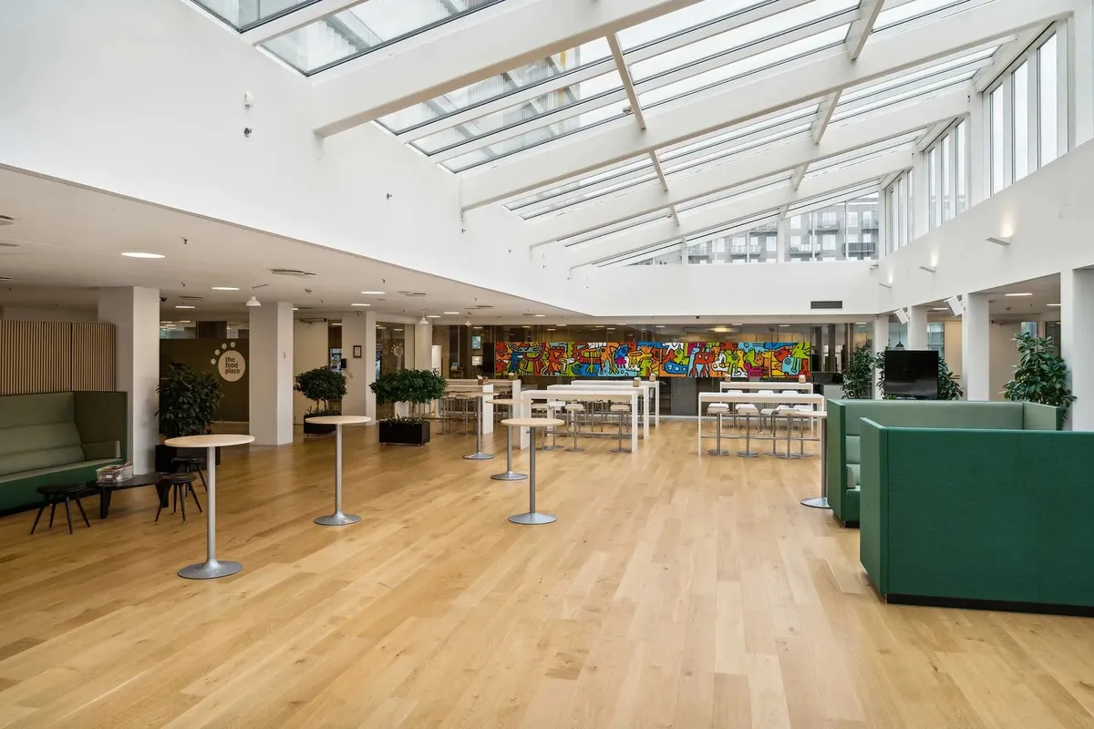 Store åbne rum med lyse lofter, lysegulve, møbler og vægmalerier, samt planteelementer