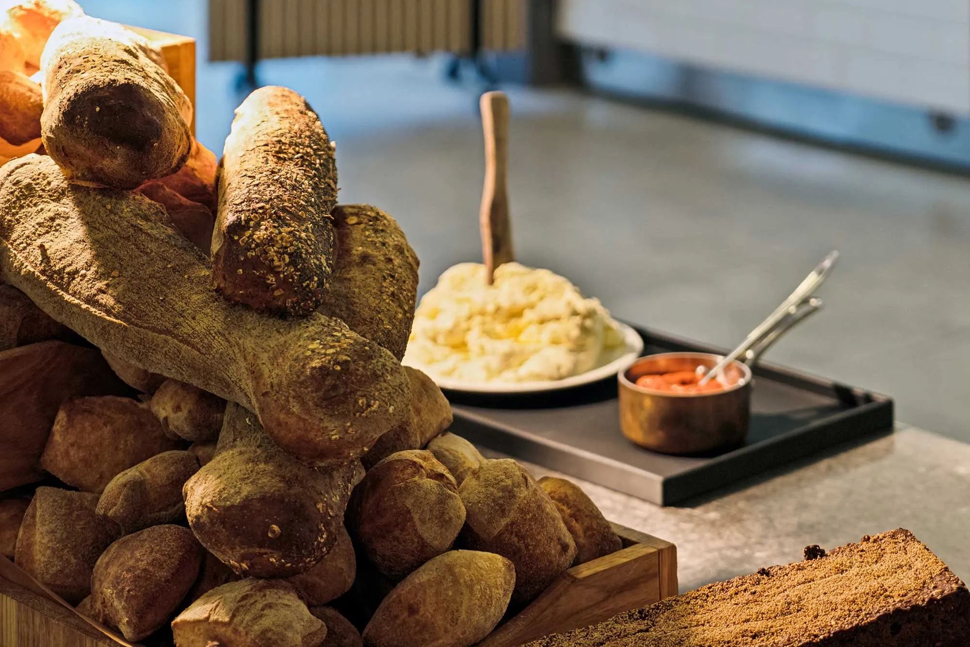 En række hjemmelavede brødknoller med valnødder, der er samlet i et træskab og serveret med en skål smør og en skål rødbeder