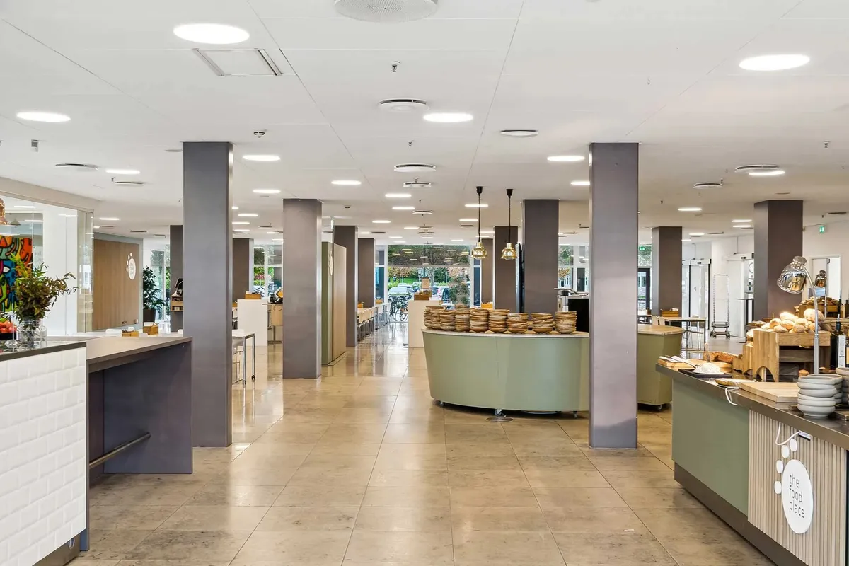 Moderne fællesområde med lyse lofter, højt loft, rundt brødrister, og dekorationer på væggene