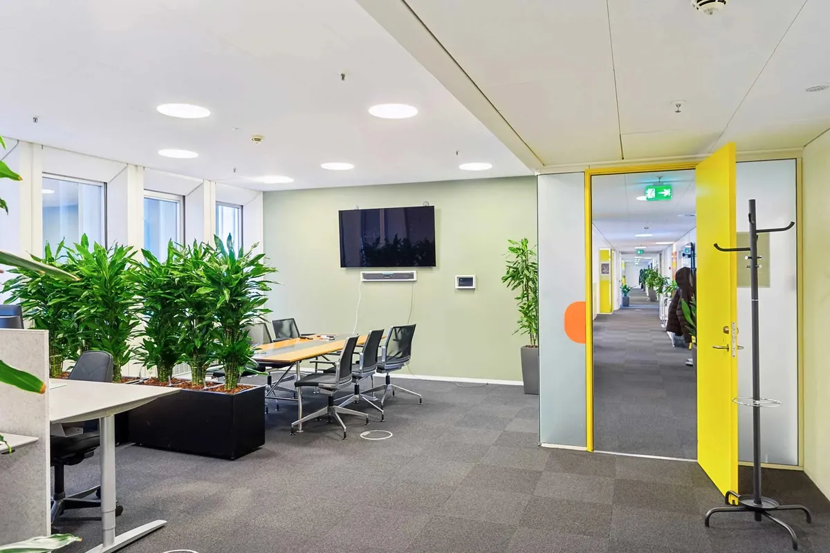 Moderne kontor med store vinduer og indretning med plantegrønt og møbler til konferencer og samarbejde