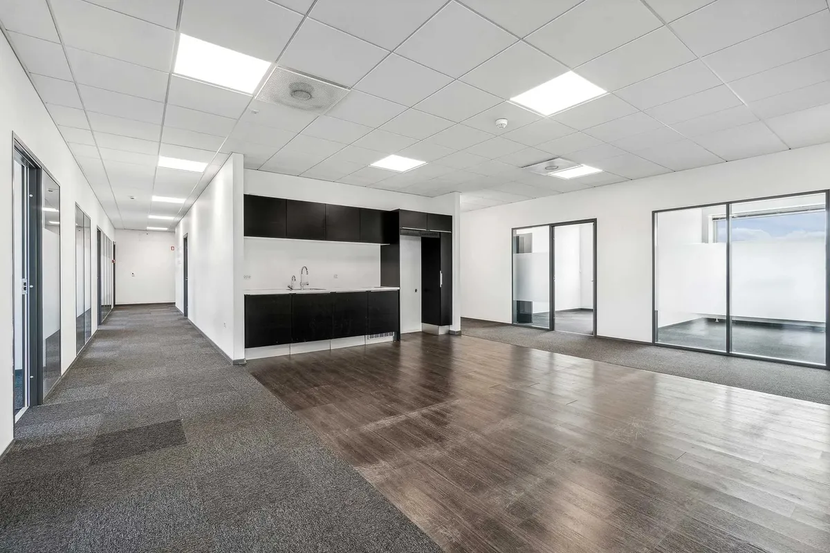 Kontorbyggeri med lyse lofter og gulvbelægning samt lyse glasvinduer og hvide vægge