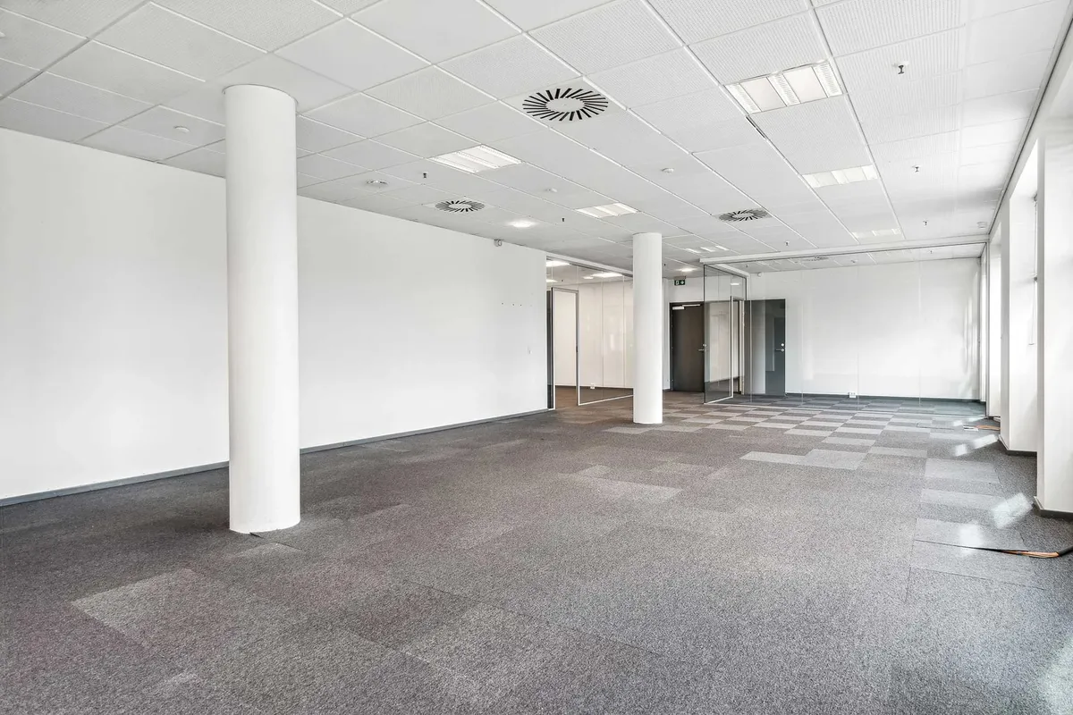 Foto af glasdør og højt loft i en stor, tom kontorbygning med lyse gulve og hvide vægge