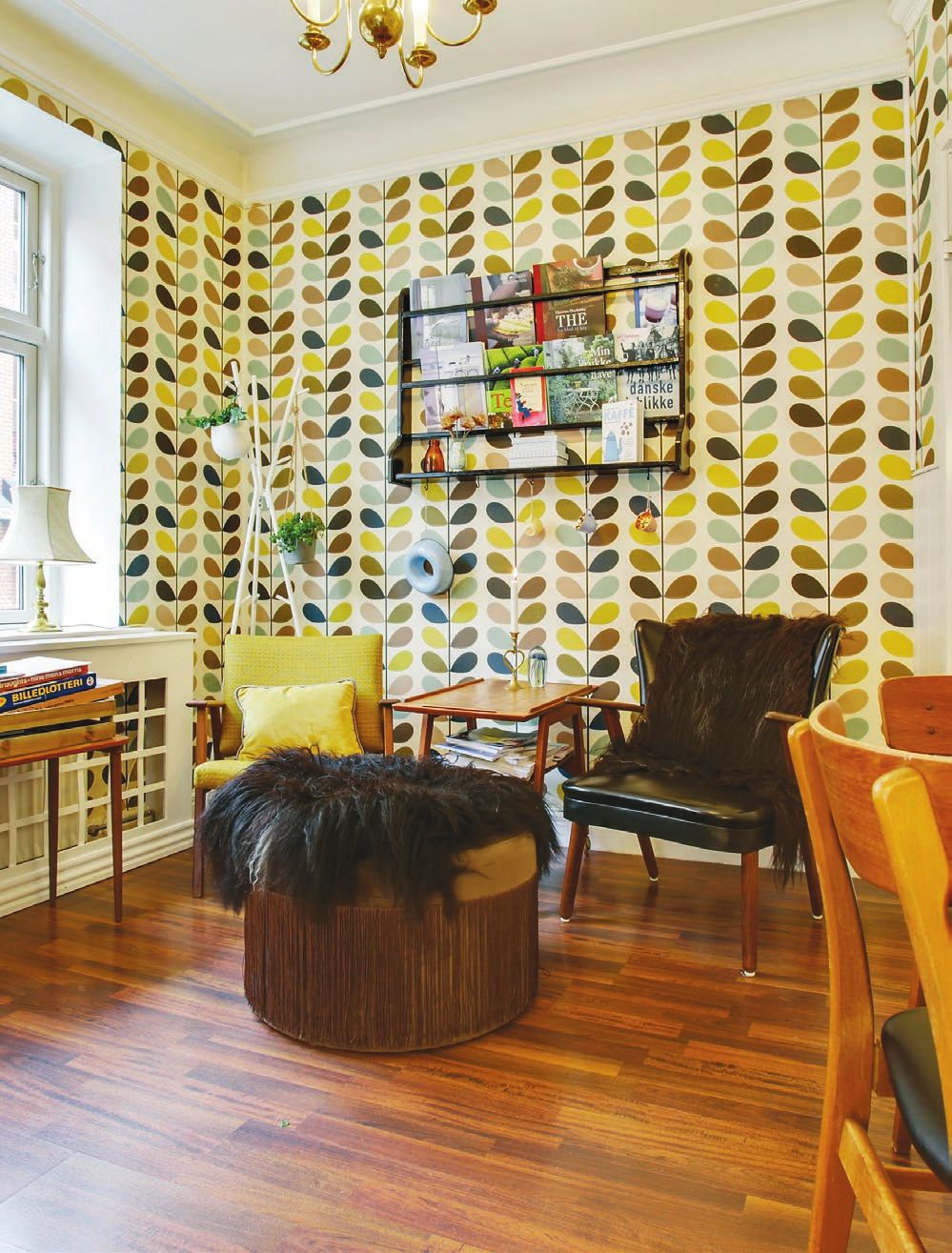 En hyggelig stue med retroindretning og brun gulv med møbler og læsestue med flere hylder og plante i lysekronen