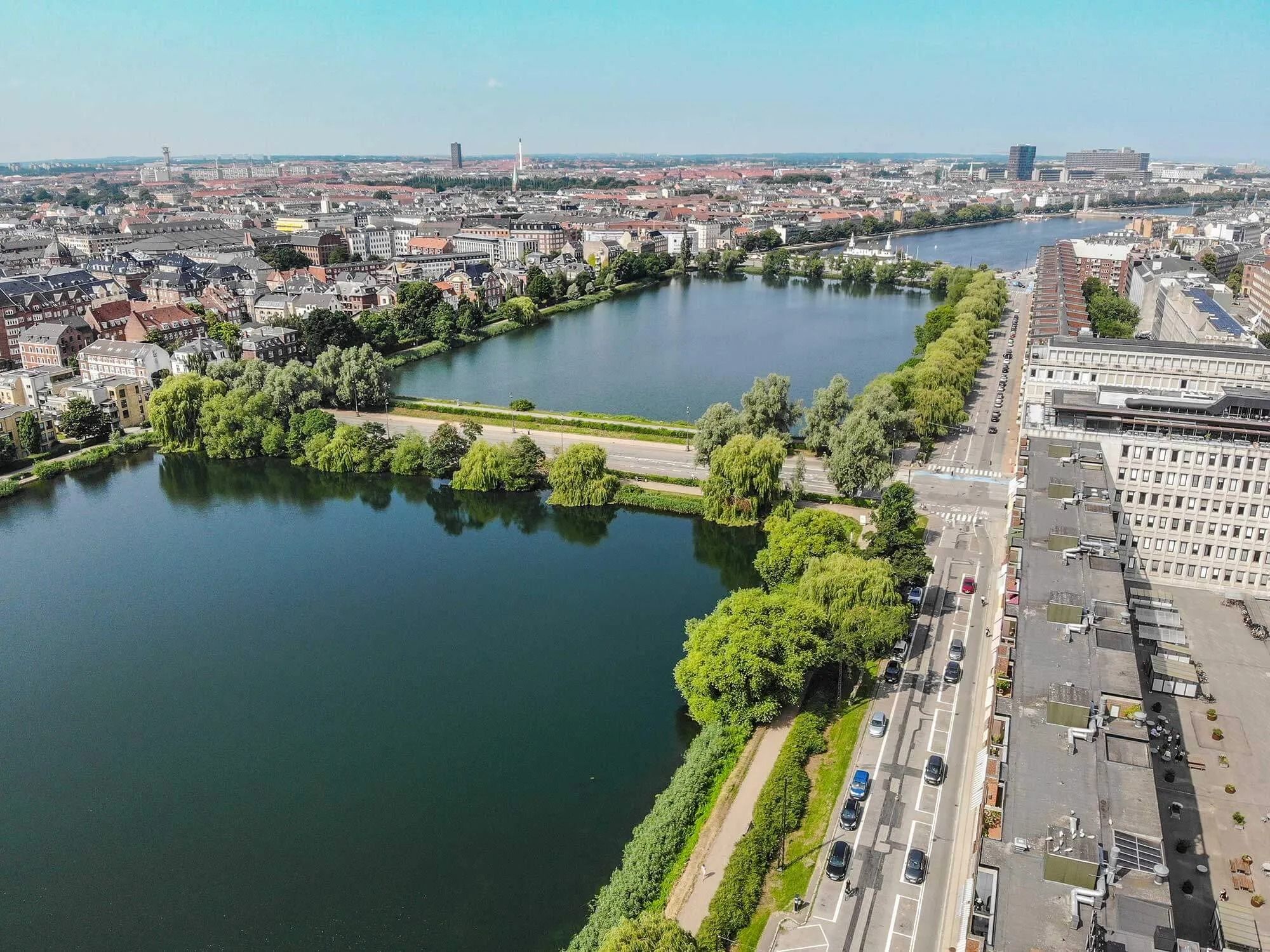 En luftfotooptagelse af København med smukke grønne parker og en bred vandvej, der deler byen i to
