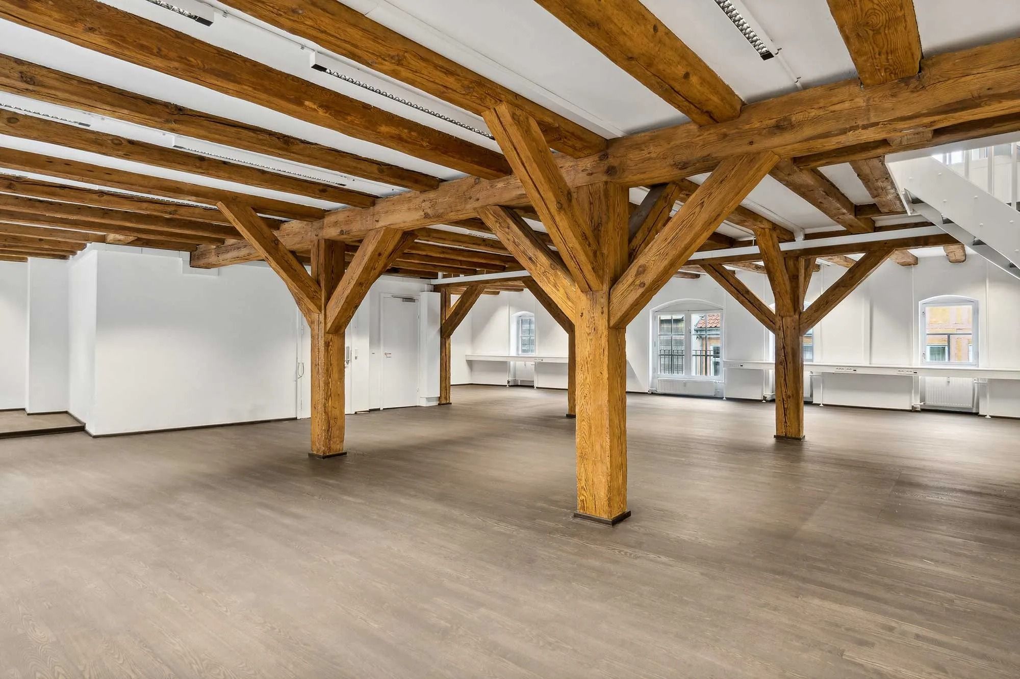 Moderne loft med lyse bjælker og lysegul gulvbelægning, fuldstændig ubeboet rum med hvide vægge og åbne ruder med udsigt til