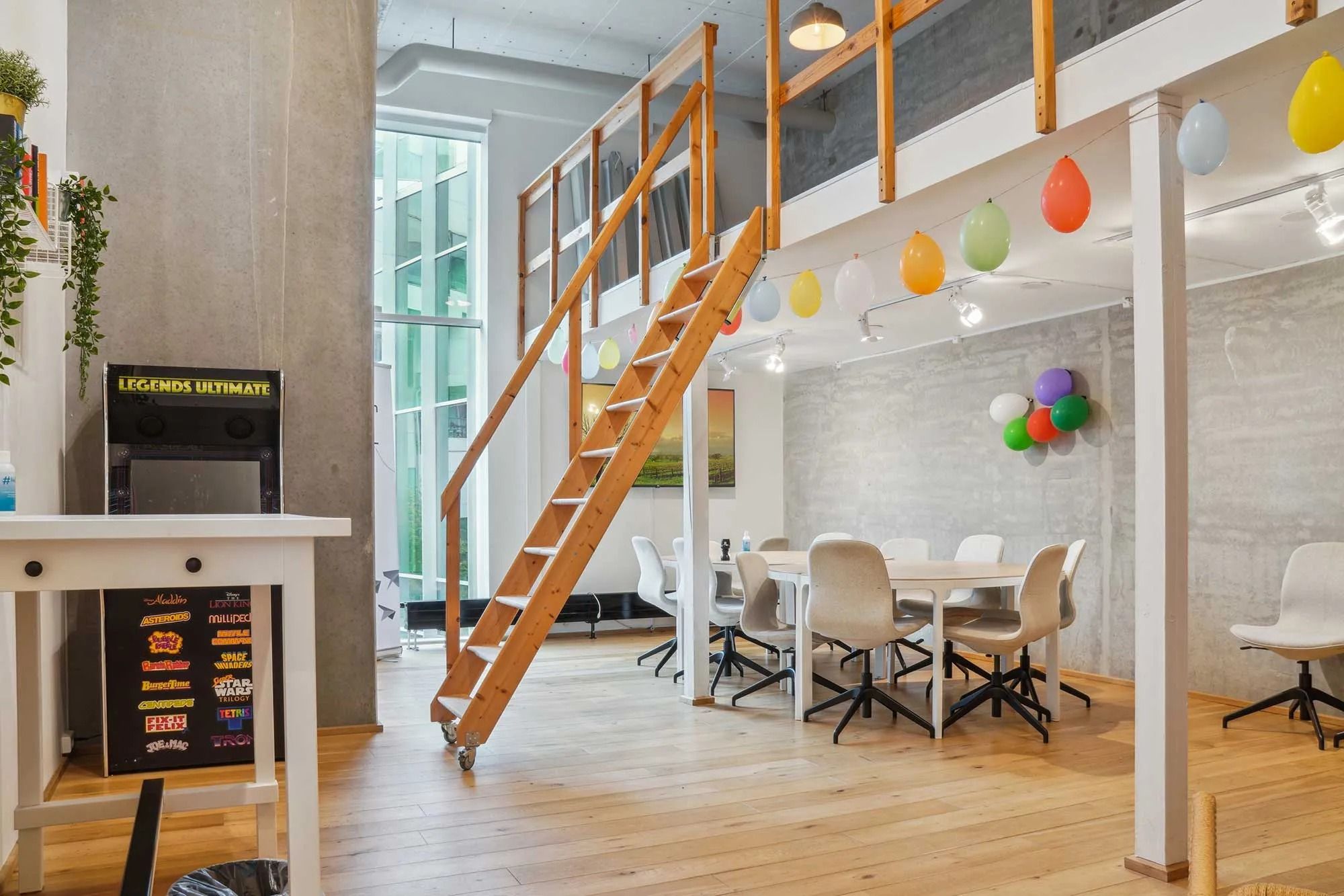 Kontorlokaler med loftsrum, lysekroner og lysepunkter, stolpe med farvede balloner, et bord med stole og en gammel