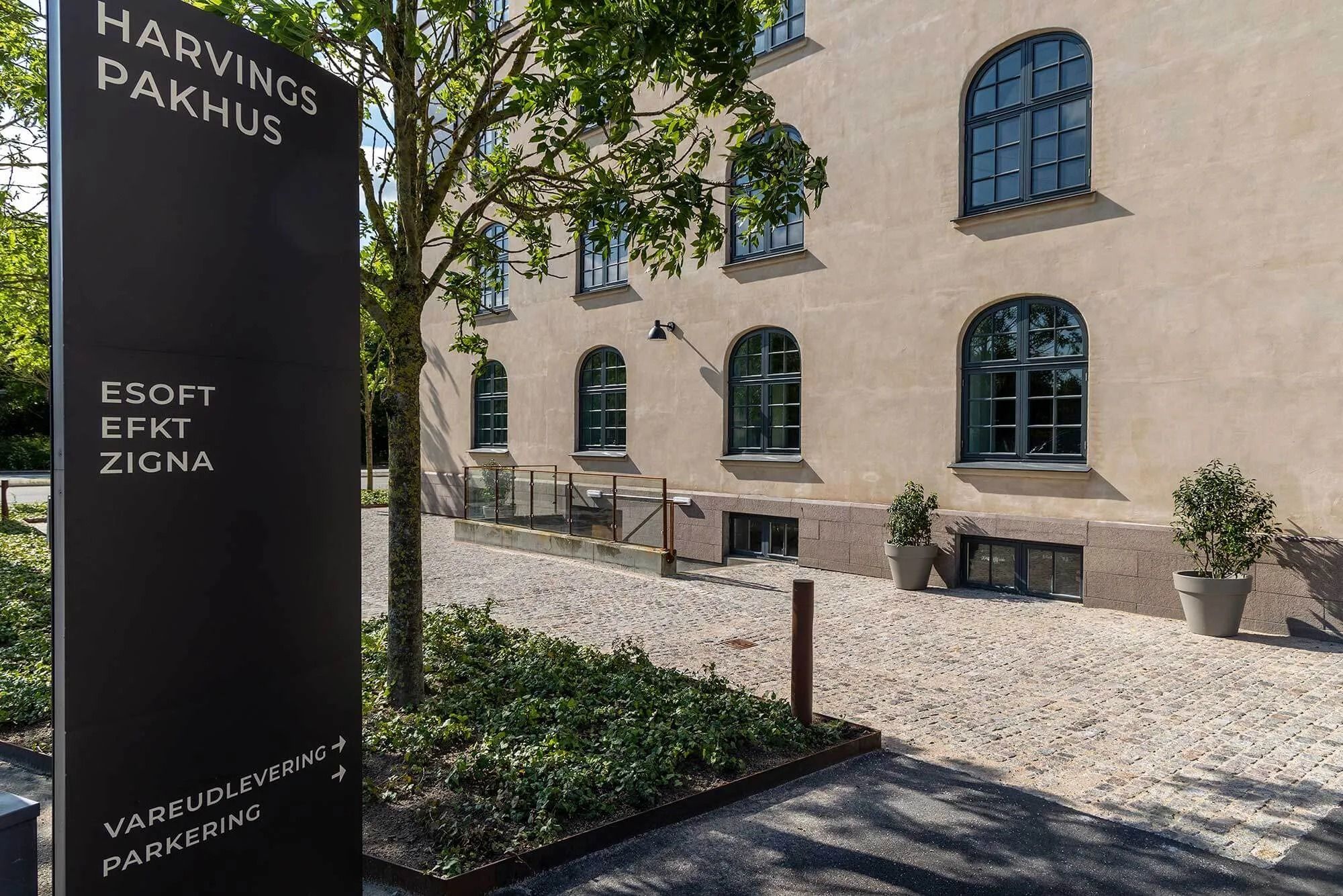 Harvings Pakhus med vareudlevering, parkering og et stort vindue på første sal