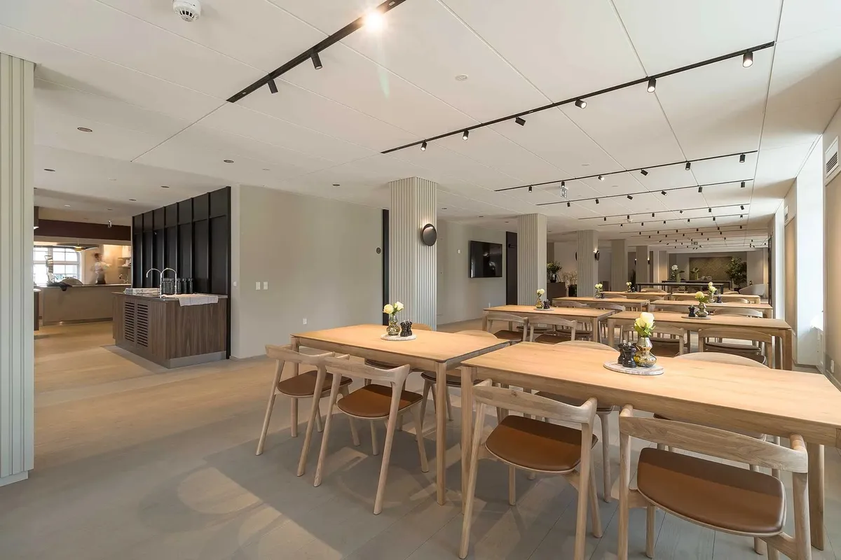 Moderne kontor med åben kantine, møbler og lyse loftslamper i hvid og beige farve