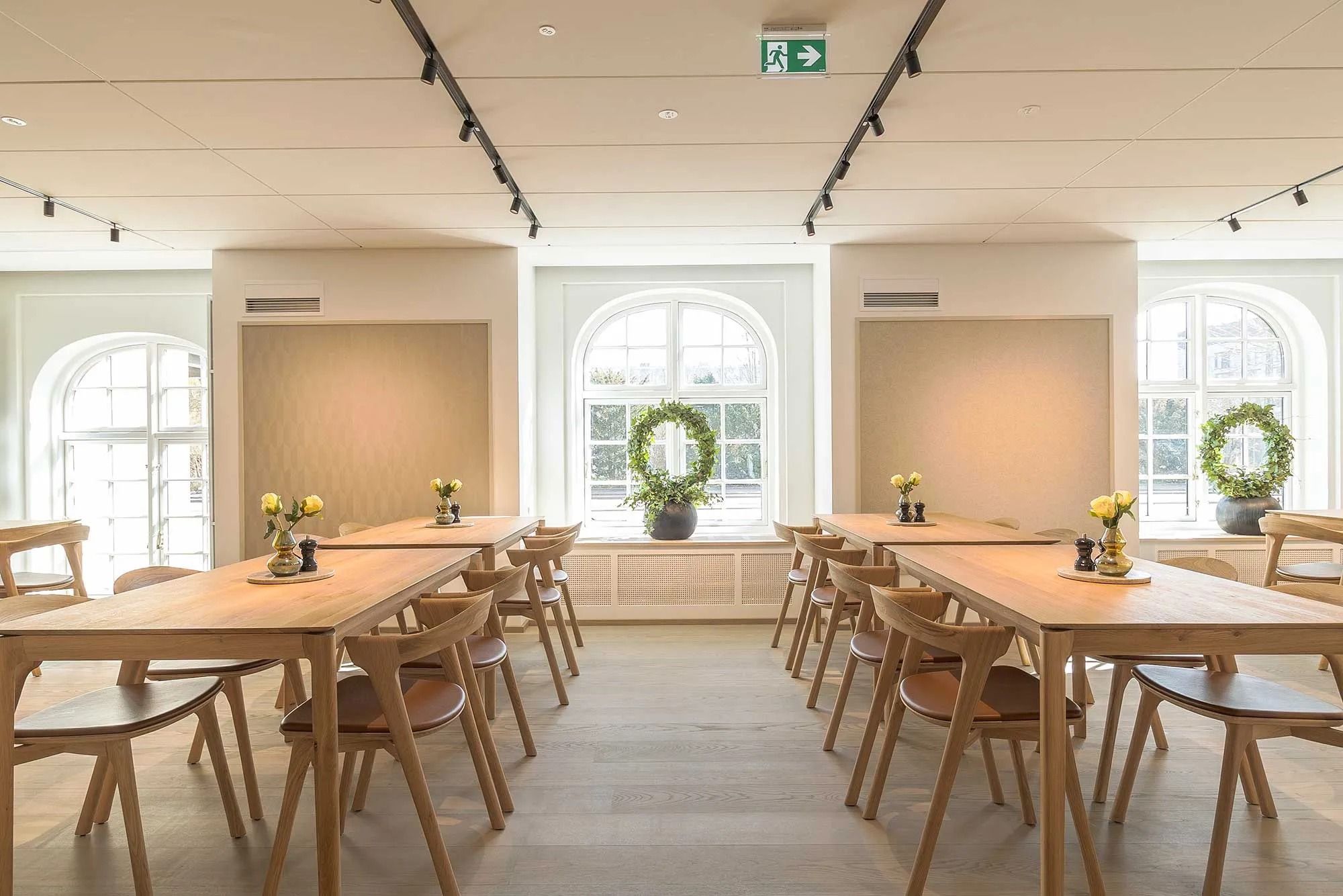 Elegante kontorlokale med lyse vinduer, moderne møbler og plantekranke i hjørnerne