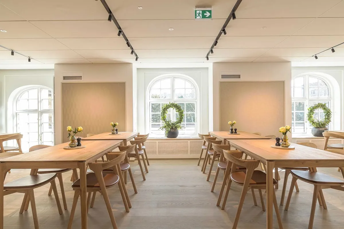 Elegante kontorlokale med lyse vinduer, moderne møbler og plantekranke i hjørnerne