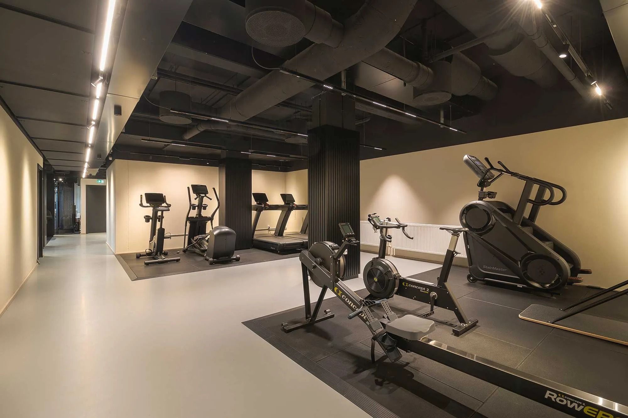 En stor og veludstyret fitness- og træningsstue med moderne og funktionelle fitnessapparater og gulve, samt en guldvæg i