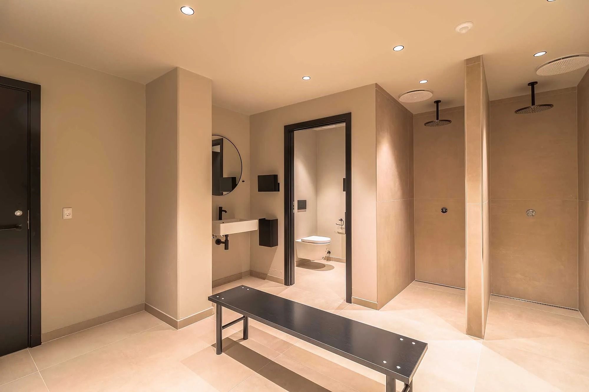 Elegant og moderne toiletrum med højloftede rum og flotte lysekroner. Et badeværelse med moderne brusebad, toilet og spejl.