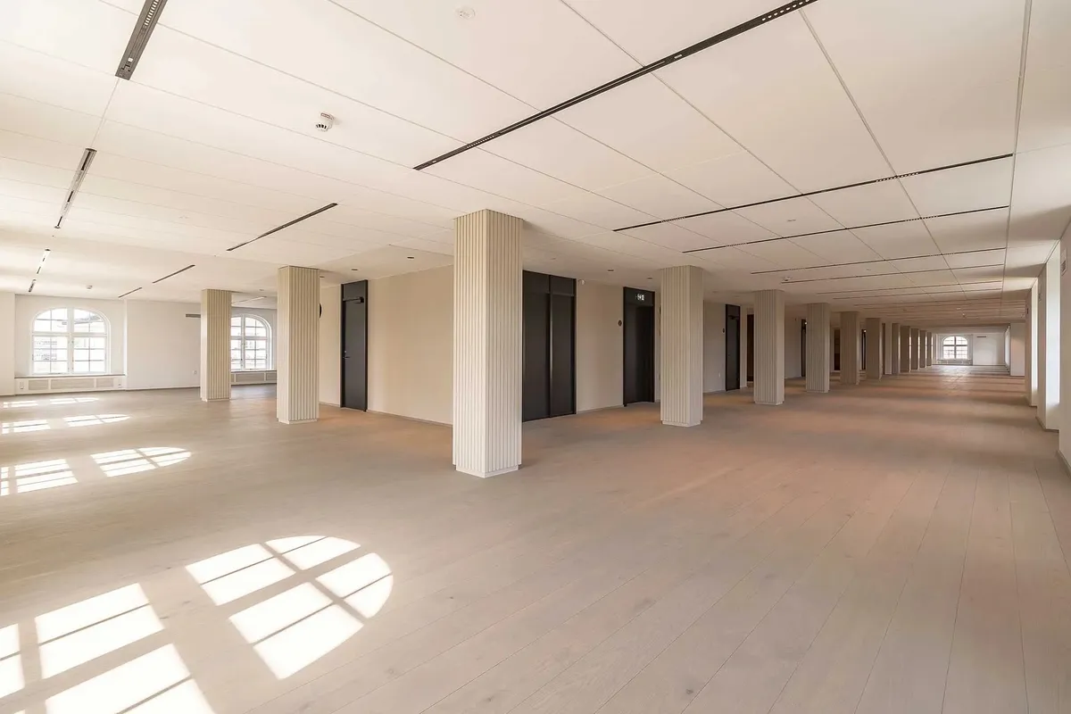 Elegant indretning med lyse gulve og hvide vægge samt store vinduer og højt loft