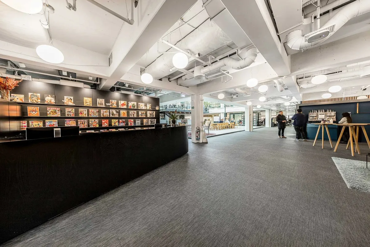 Personer går rundt og ser på hylderne med bøger og tegneserier i et stort rum