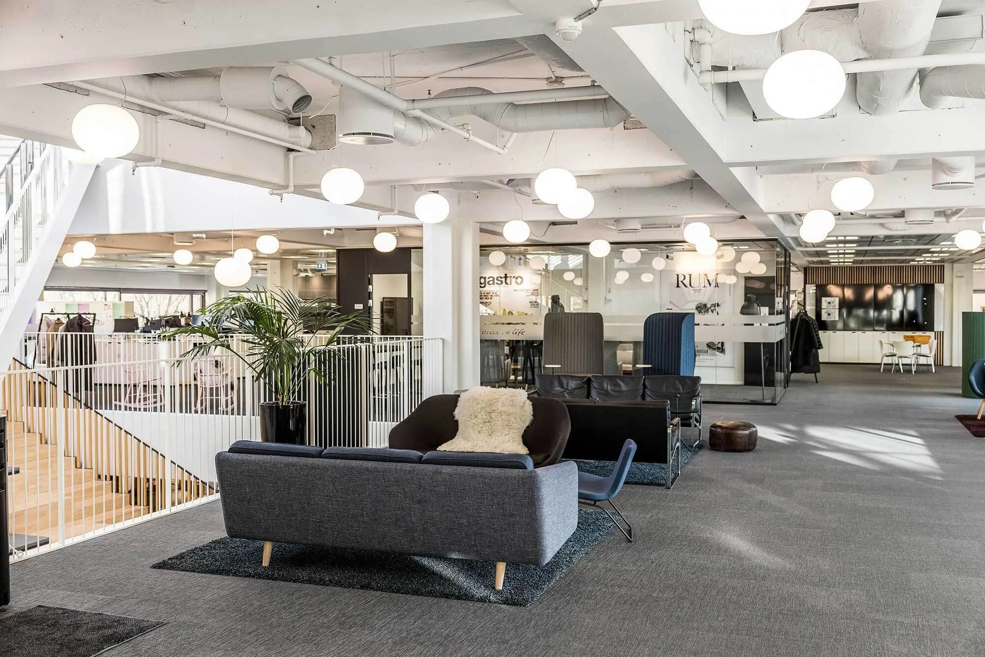 Kontor med sofaer og møbler, hvor der er en stor terrasse med plante og lysekroner