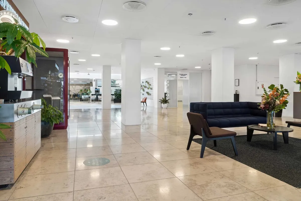 Moderne lobby med højloft, træmøbler, blomster og møbeludstykning samt skrift og logoer