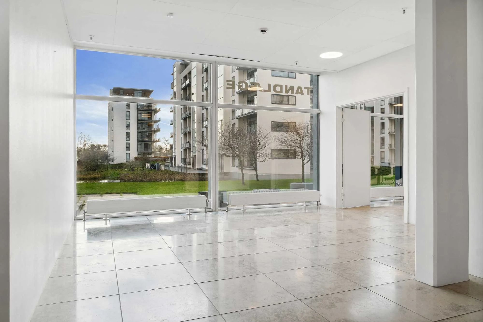 En stor lobby med lyse hvide vægge og gulve samt glasvinduer og døre