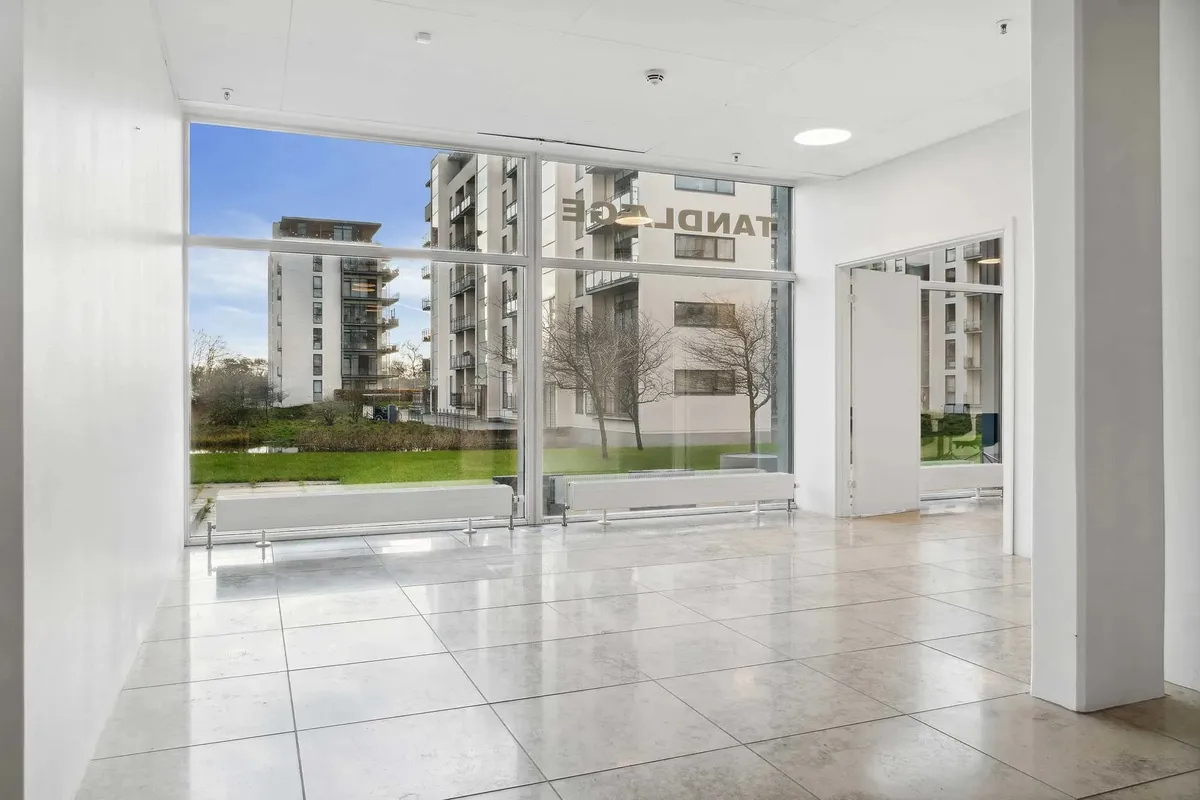 En stor lobby med lyse hvide vægge og gulve samt glasvinduer og døre