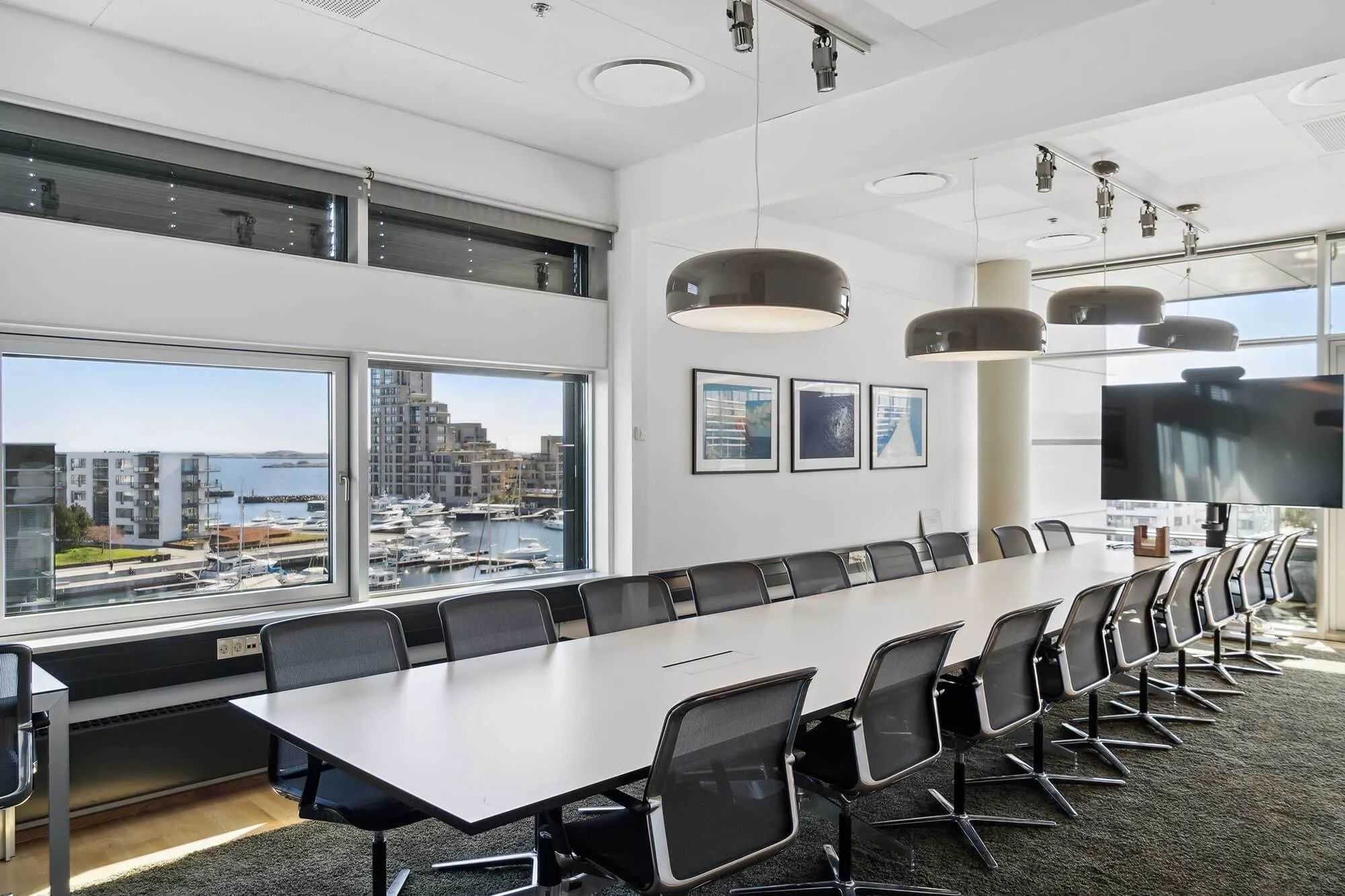 Mødelokale med langt hvidt bord og stole og udsigt til by og havn