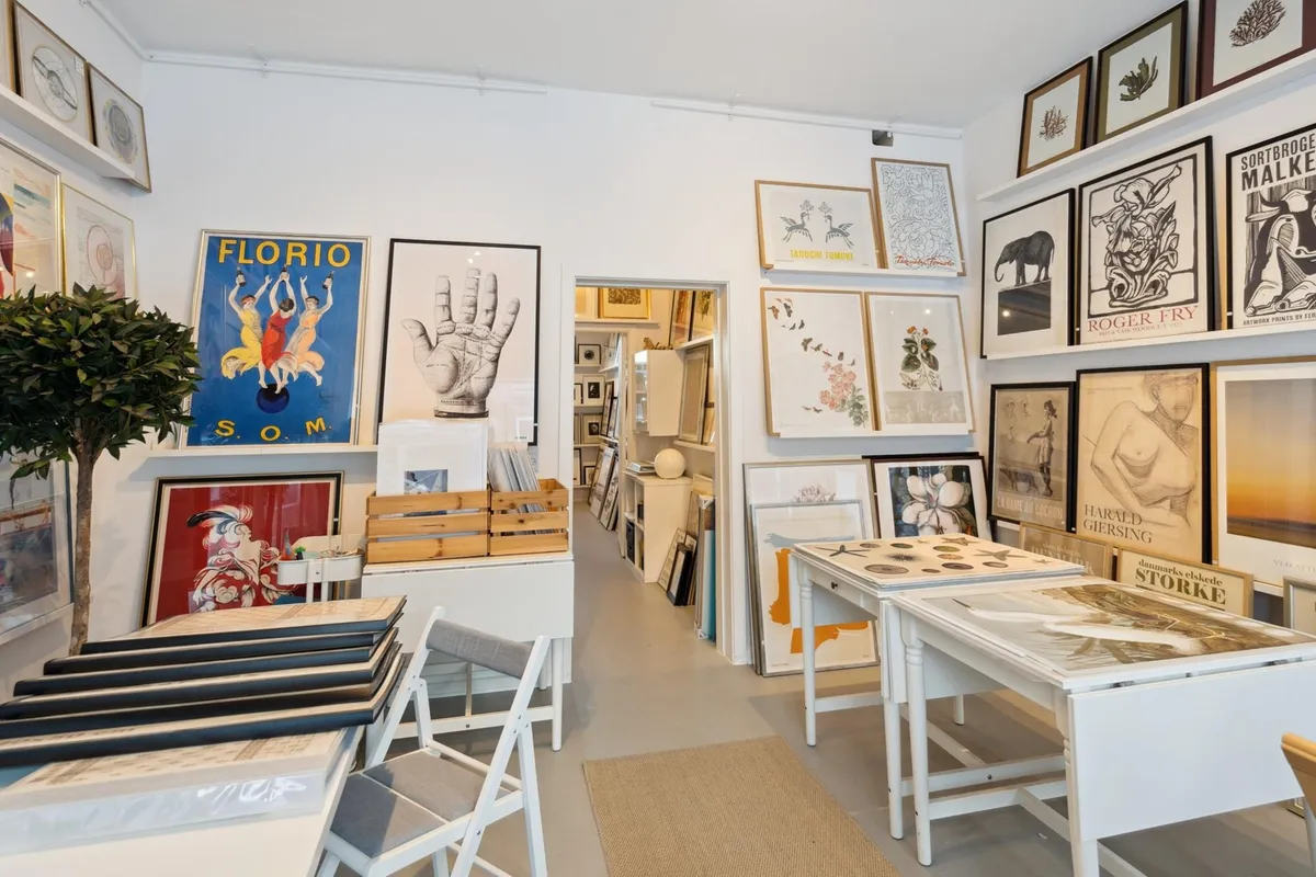 Moderne butik med kunstværker og håndlavede produkter på hylderne og flere stole og borde i rummet