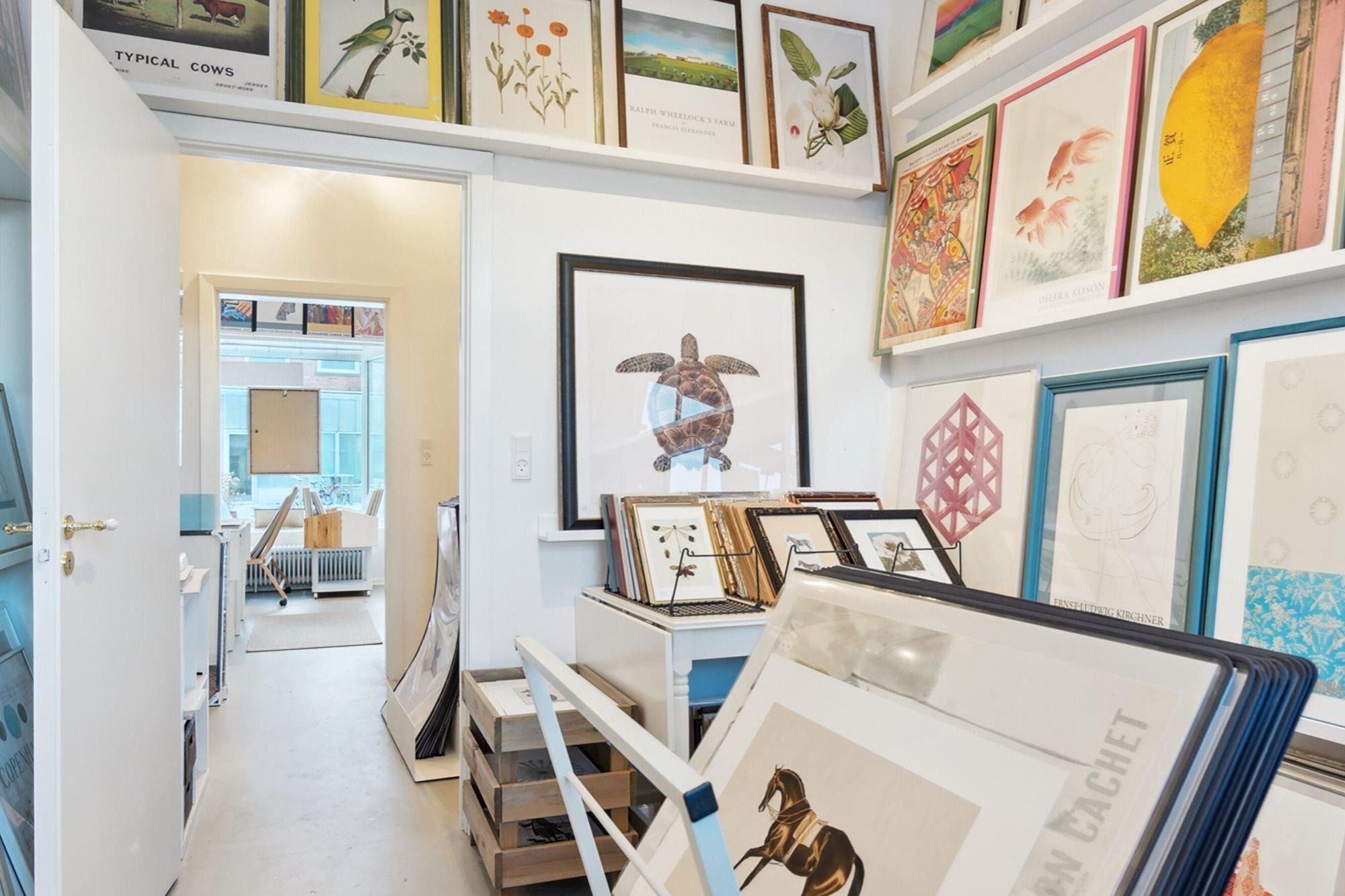 Kunstgalleri med mange kunstværker, herunder flere indrammede malerier, som en skildpadde og en hest