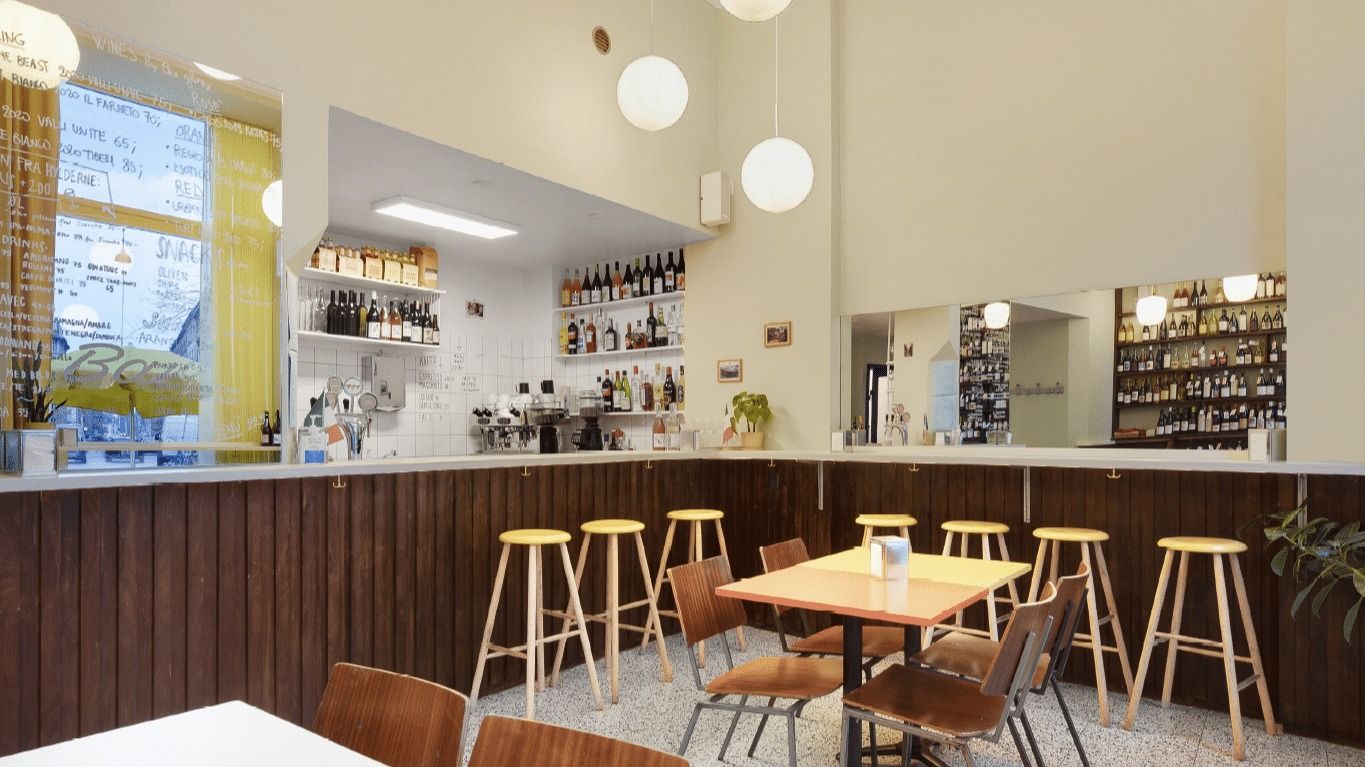 En nyrenoveret vinbar med lyse loftslampe, brun træbardisk og høje stole til at sidde på