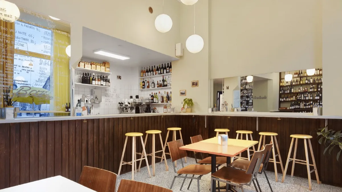 En nyrenoveret vinbar med lyse loftslampe, brun træbardisk og høje stole til at sidde på