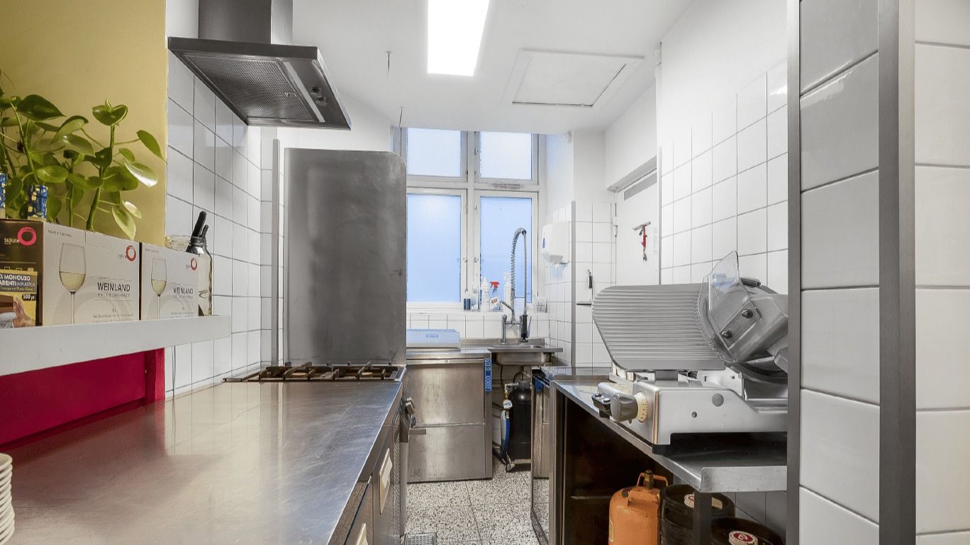 Et renset køkken med flere apparater og en spisestue med borde og stole.