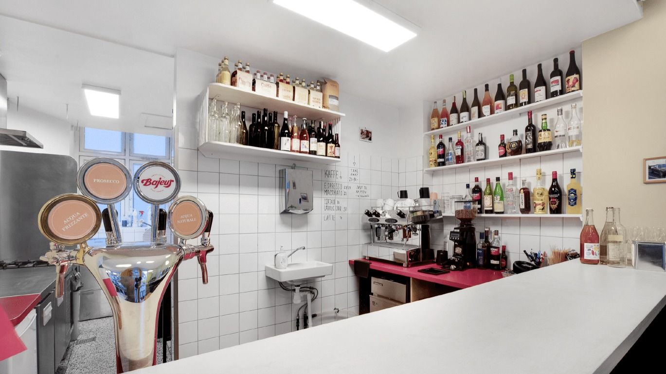 Indkøbsvogne og brændbare væsker i et café-lokal med en kaffemaskine og flere alkoholiske drikke på hylder