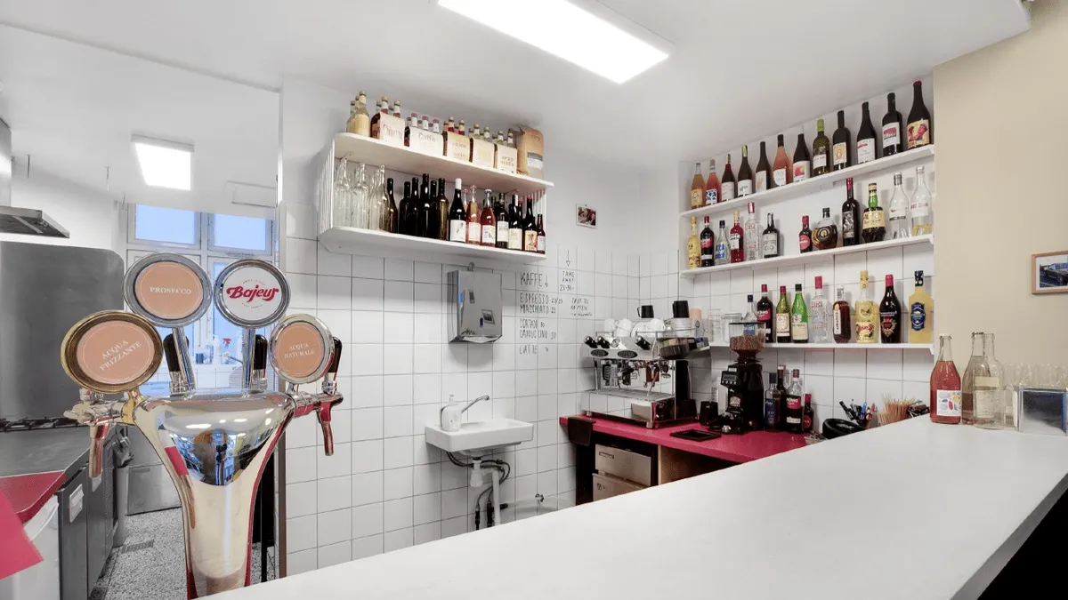 Indkøbsvogne og brændbare væsker i et café-lokal med en kaffemaskine og flere alkoholiske drikke på hylder