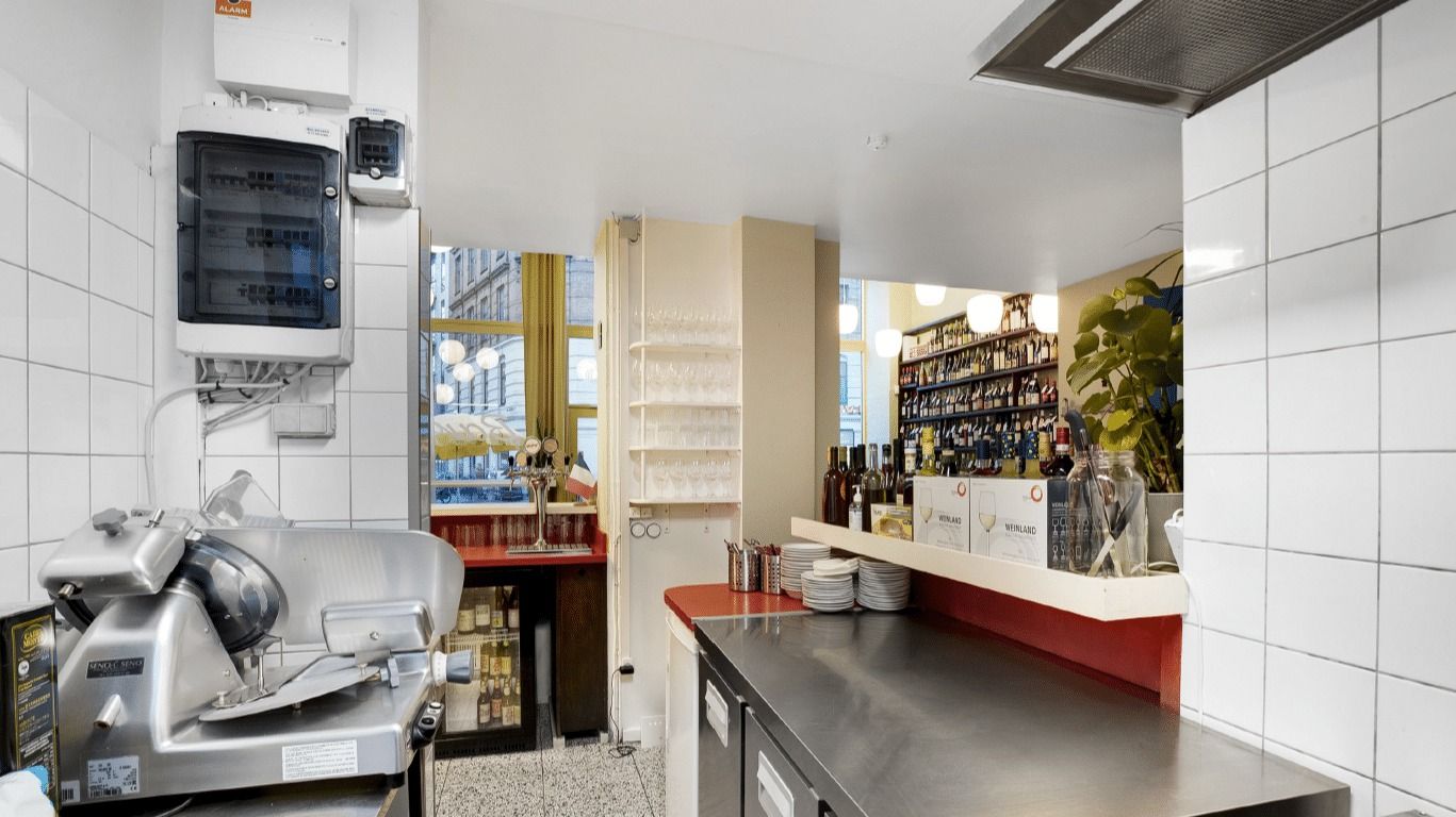 En stor, lys og åben stue med køkkenudstyr og en stor, køleskab i højre side.