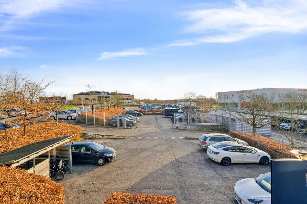 Garage med parkerede biler og stier langs bygninger i Horlys, med en Tesla Model 3 og en Tesla Model S parkeret i garagen