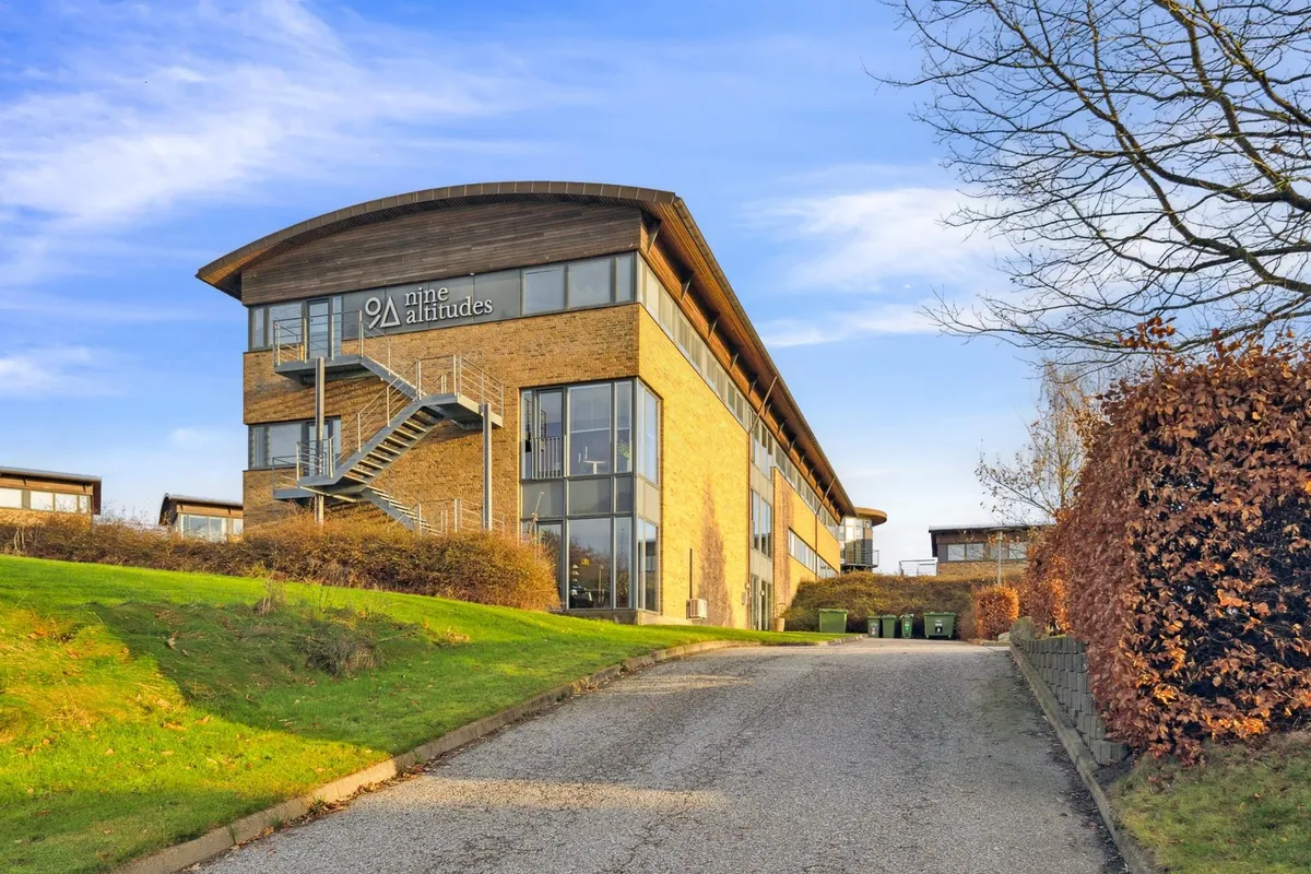 Kontorbyggeri med glasvinduer og trapper mod facaden Navnet Nine Altitudes synes at være på bygningen Styrket terrasse med