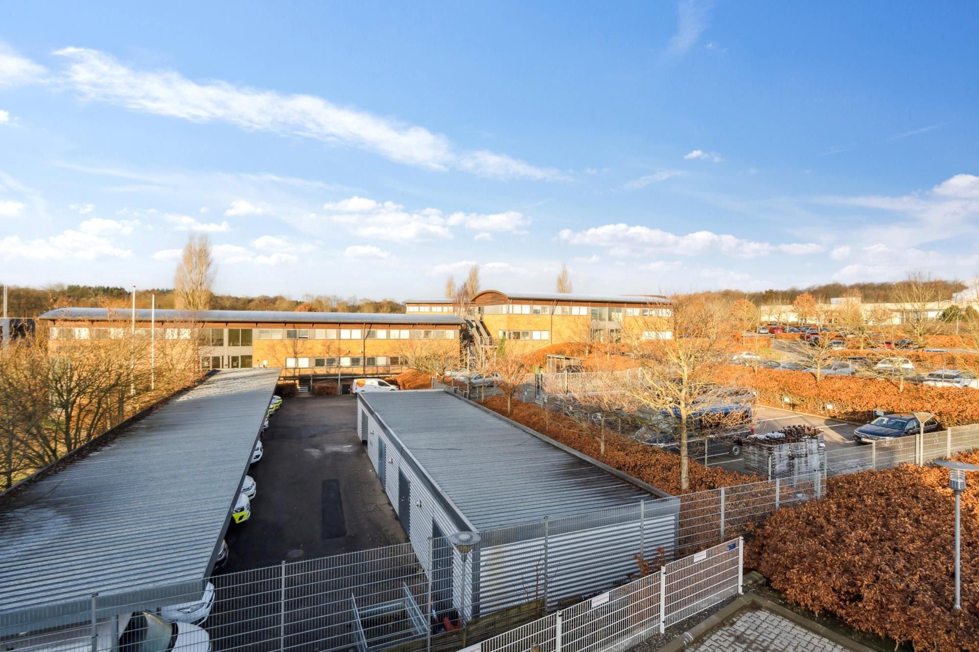 Moderne kontorejendom med garage, parkeringsplads og flere biler og flere lejemål, udendørs foran bygningen med lyse vinduer