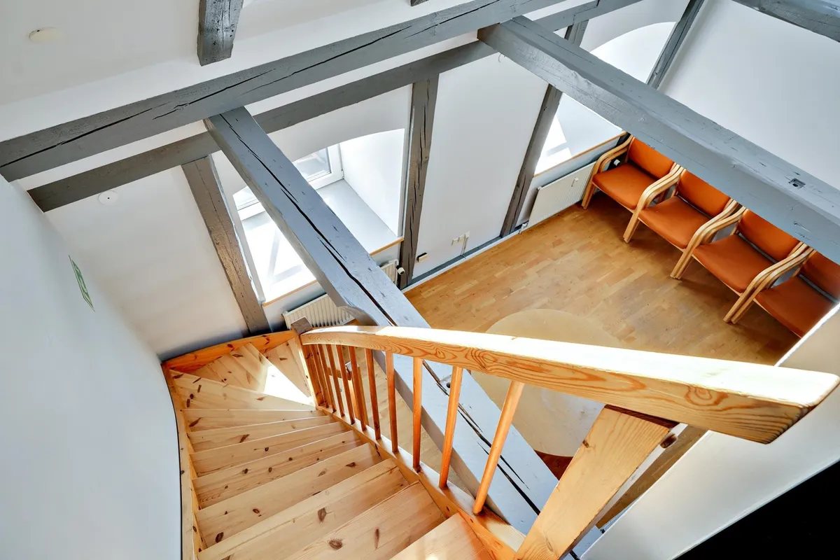 Trætrapper og gulv med lyse nuancer og store vinduer med solskin og lysegul trægulv