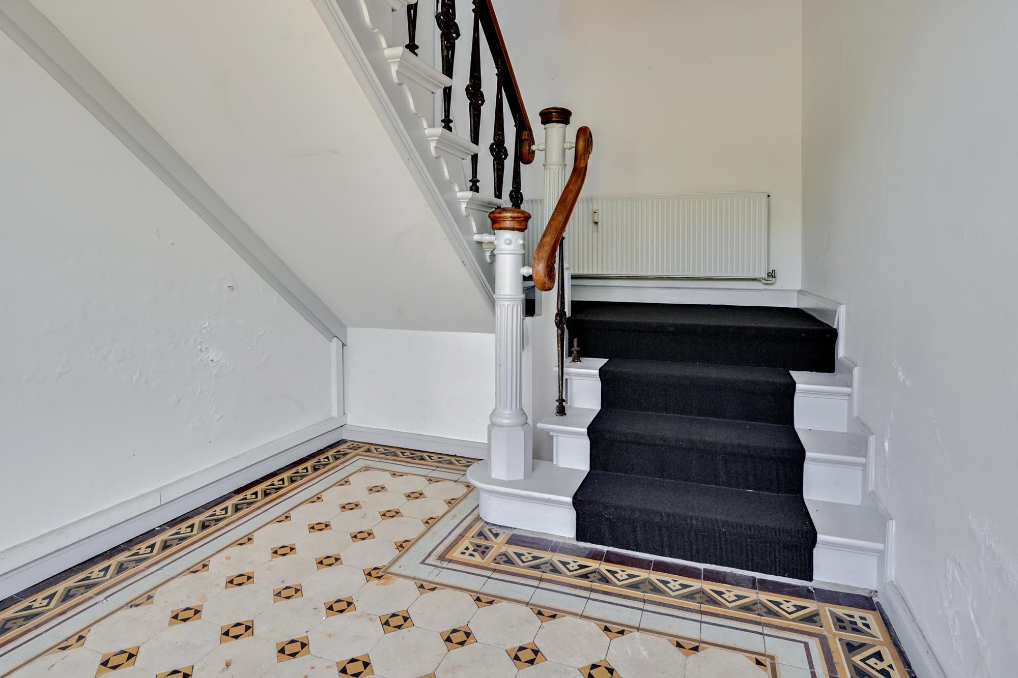 Sort trappe med håndtag og hvid marmor forsynet med gulvtæppe og marmorgulv i vinderen.