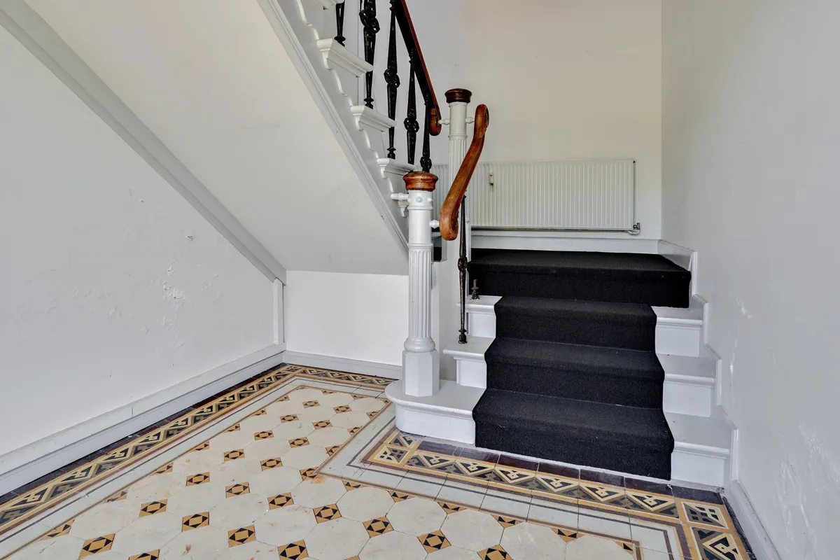 Sort trappe med håndtag og hvid marmor forsynet med gulvtæppe og marmorgulv i vinderen.