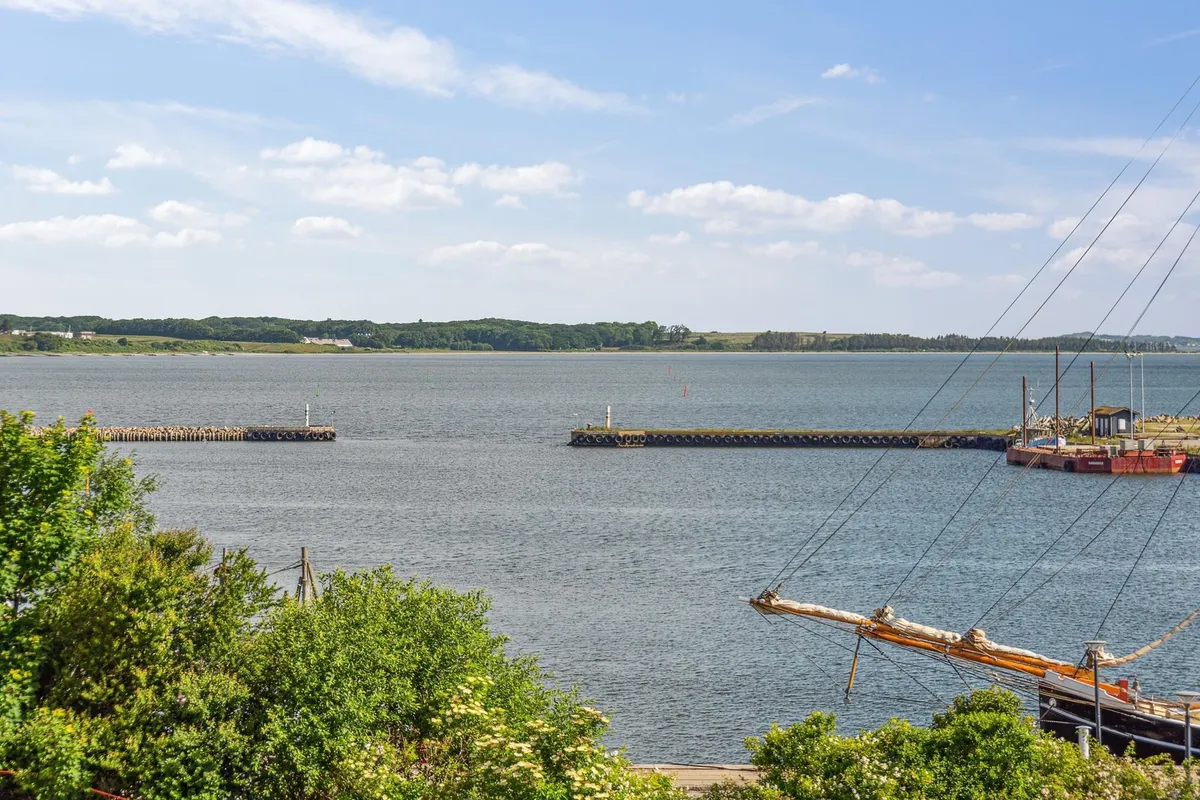 En havn med en flot udsigt over vandet og en sejlskib og en gul båd i vandet