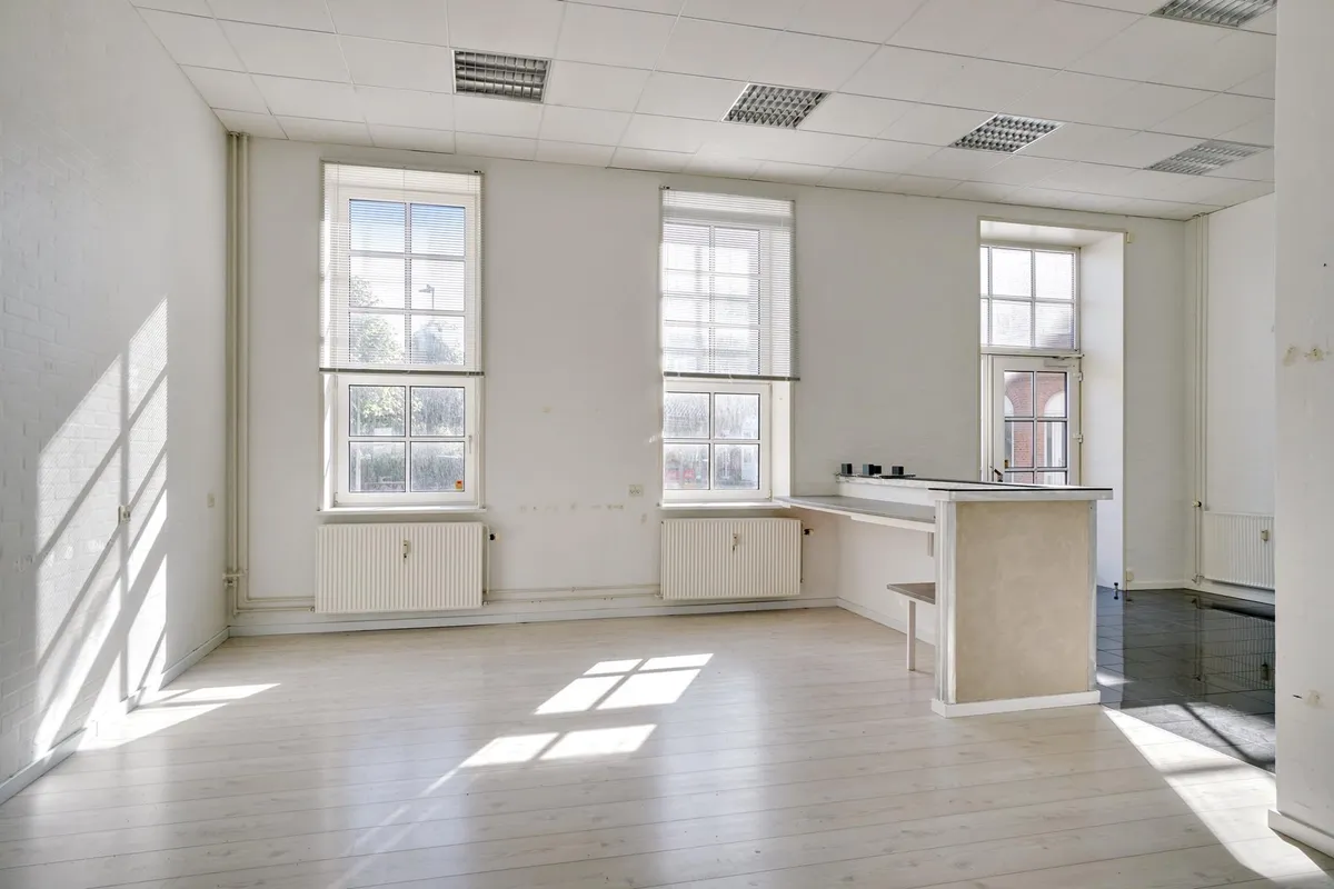 Store tomt med udvendige ruder og store vinduer samt lysegult gulv og hvide vægge