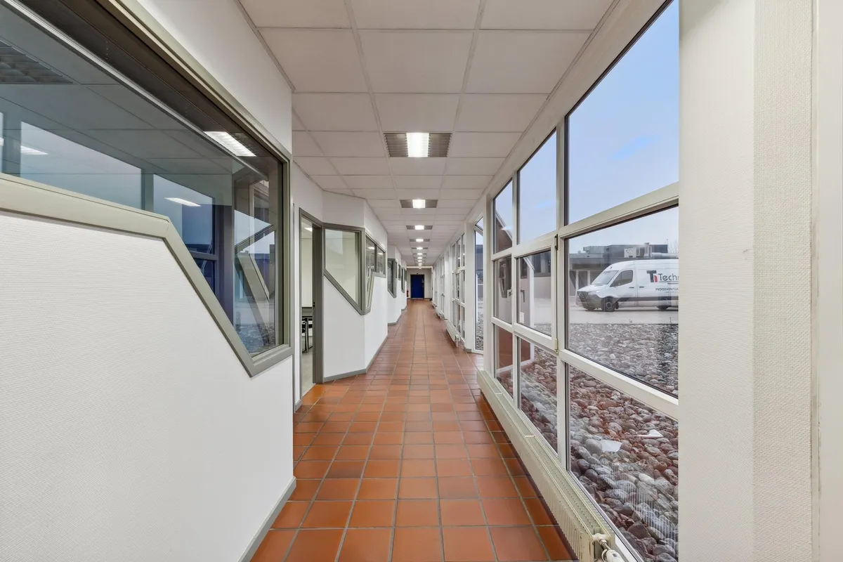 En hal med lyserøde klinkergulve og glasvinduer der går langs hele væggen